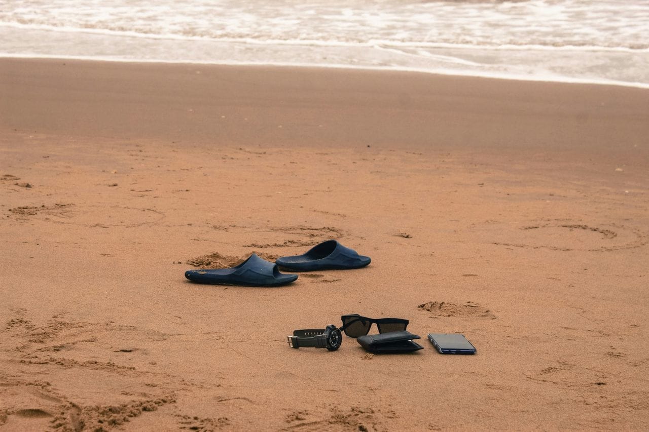 Strand, törölközők, napernyő, szalmakalap, papucs a homokban